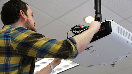 CTL support staff member fixes projector ij a classroom